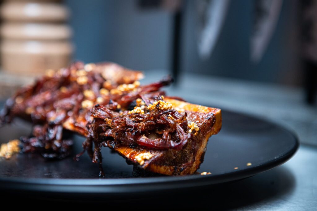 Gegrilde vleesbrood met rood bietensalade op zwart bord, kamado BBQ gerecht