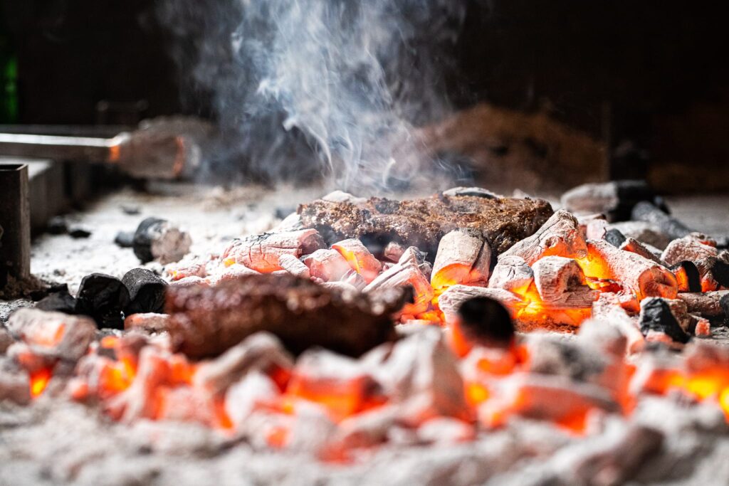 Gloeiende houtskoolkamado met levende vlammen, as en rook voor BBQ koken
