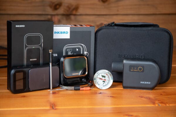 INKBIRD BBQ thermometer set met wifi display, analoge thermometer en transporttas op houten tafel.
