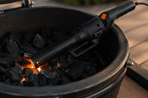 Kamado barbecue met brandende kolen en zwarte vuurpijp gereedschap